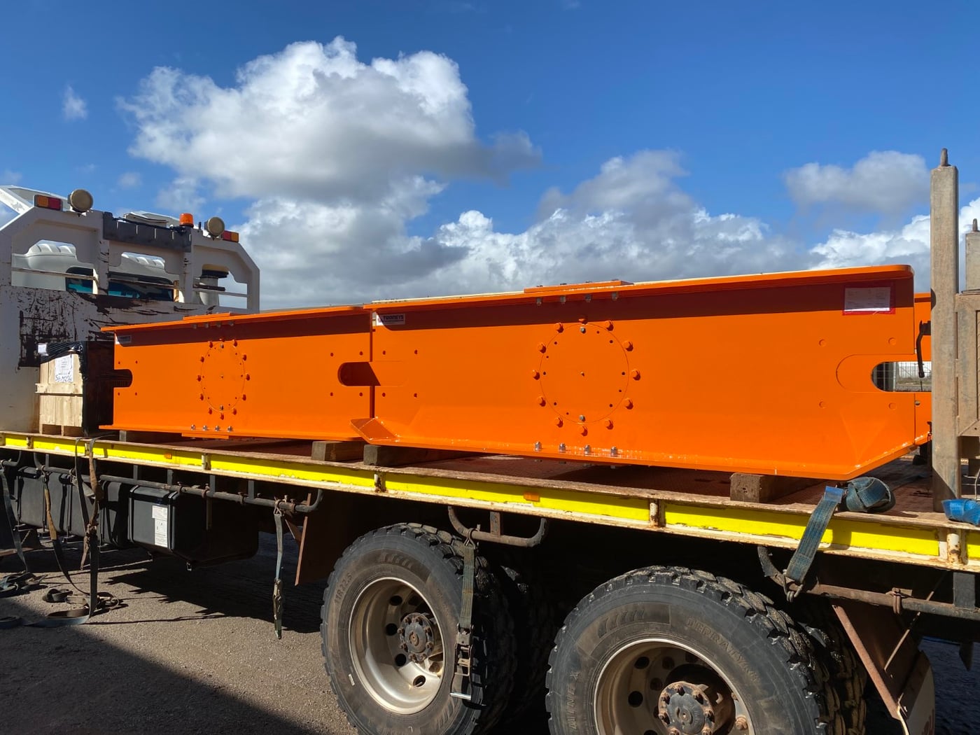 Orange painted fabricated steel beam strapped to a flatbed truck ready for delivery