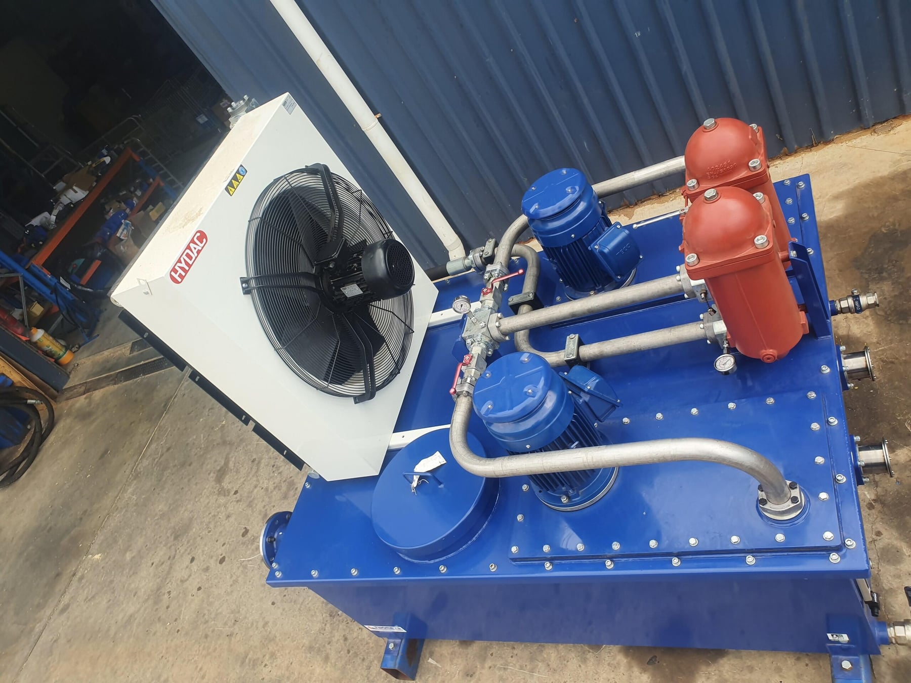 Blue hydraulic power unit with cooler, pumps and filter housings built up on a fabricated tank