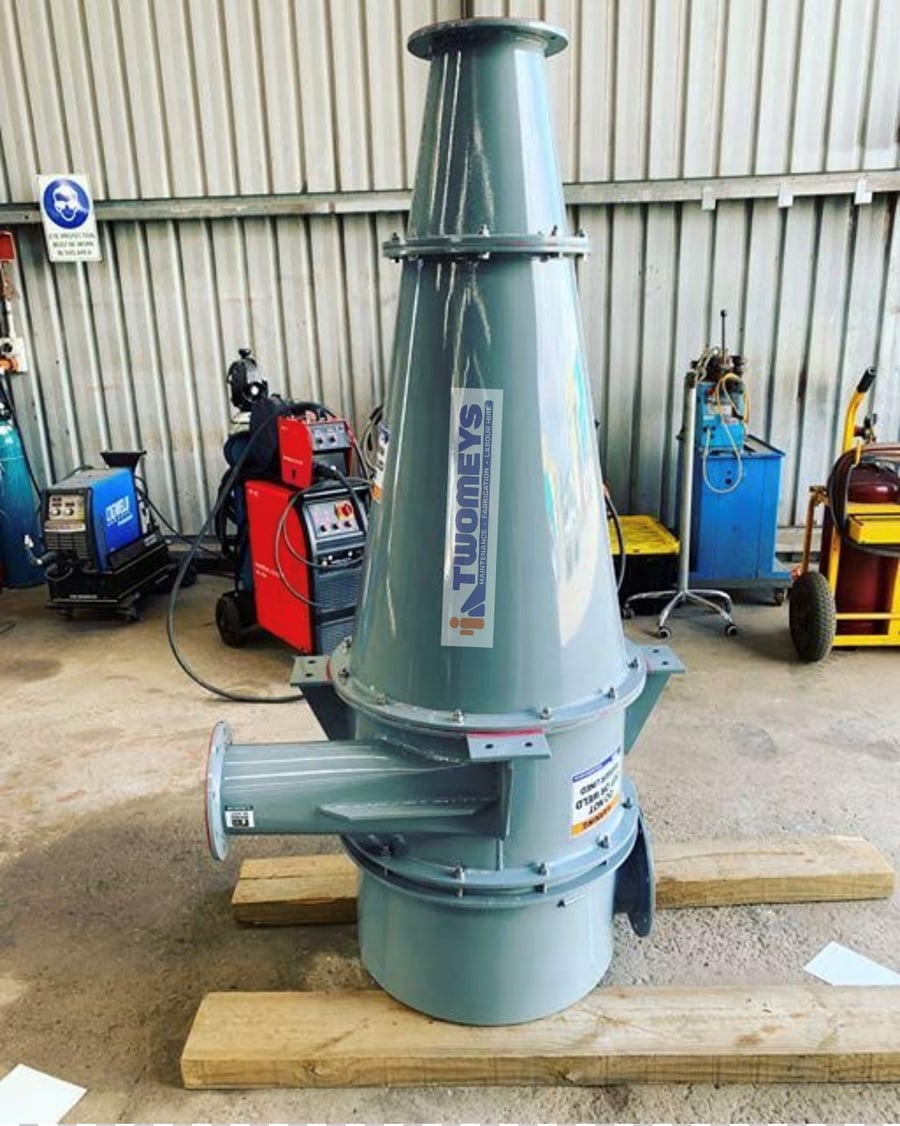 Painted fabricated cyclone with flanged inlet and outlet standing on timber bearers in the workshop